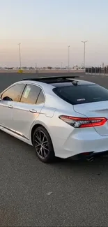 Sleek white sedan parked at sunset on an open road.