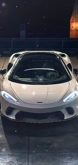 White sports car in a dimly lit urban parking area at night.