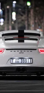 White sports car on city street at night, rear view.