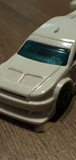 White toy car on a wooden surface wallpaper.