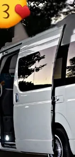 White van with open door at dusk, highlighted by night scene and trees.