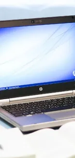 Modern desk setup with laptop and open books in light background.