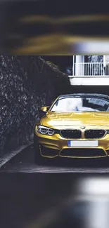 Yellow luxury car parked by a stone wall.