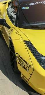 Yellow sports car parked on pavement, showcasing sleek design.