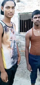 Two young men standing outdoors with a rustic background.