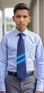 Person in a blue shirt and tie, standing indoors.