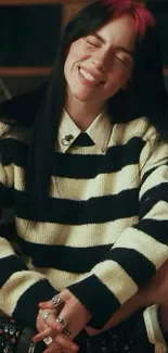 Woman smiling in black and white striped sweater in a cozy room.