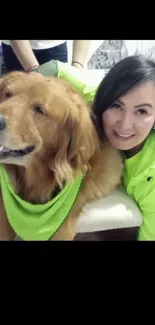 Woman and dog smiling together, wearing green outfits.