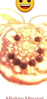 Smiley pancake with chocolate chips and emoji face on a white plate.