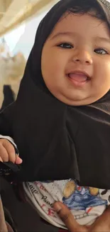 Cute baby in black scarf smiling joyfully.