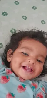 Smiling baby in strawberry-themed outfit.