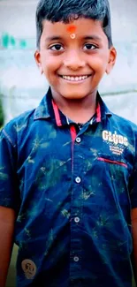 Smiling boy in a navy blue shirt against a natural background.