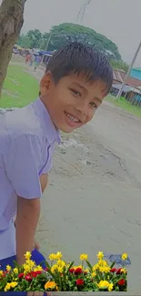 Smiling boy in nature with vibrant flowers.