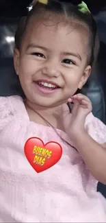 Child smiling with a 'Buenos Dias' heart graphic.