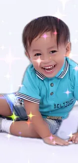 Child in blue shirt with sparkles, smiling joyfully.