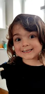 Child smiling in a cozy kitchen setting with playful expression.