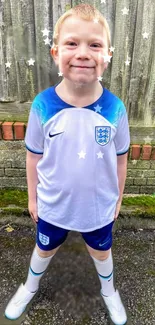 Smiling child in a blue and white soccer kit, outdoors with stars around.