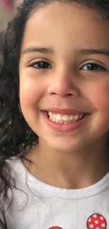 Smiling child with curly hair and white shirt.