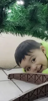 Smiling child beneath a festive Christmas tree.