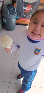 Smiling child holding ice cream indoors.