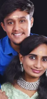 Smiling couple portrait with dark background.