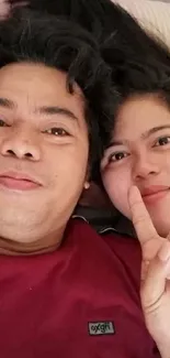 Close-up of a smiling couple with a peace sign.