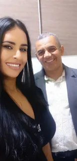 Smiling couple in elegant attire against a beige background.