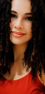 Smiling woman with curly hair in red dress.