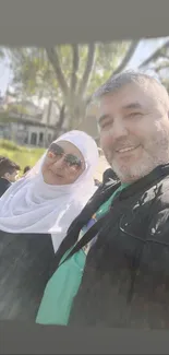 A cheerful couple smiling in a sunny outdoor setting.