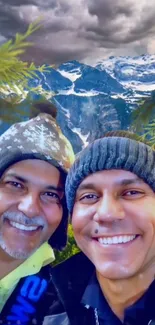 Two men smiling in front of snowy mountains under a cloudy sky.