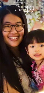 Smiling woman holding a child with a colorful bokeh background.