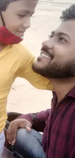 Father and son smiling warmly at each other outdoors.