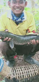 Smiling fisherman holding a catch in lush greenery background.