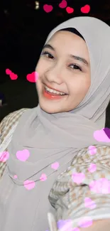 Smiling girl in hijab with pink heart bokeh effects.