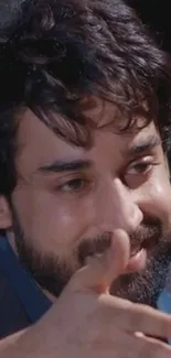 Close-up of a smiling man with a beard and dark hair in a relaxed pose.