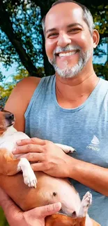 Smiling man holding a dog outdoors.