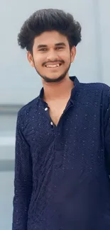 Smiling man in blue textured shirt with soft background.