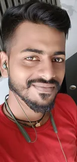 Man smiling with headphones in a red shirt.