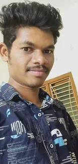 Young man in blue shirt with casual indoor background.