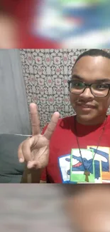 Smiling person with peace sign in a colorful shirt.