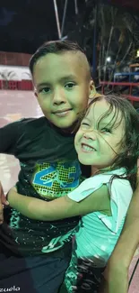 Two happy children embracing and smiling outdoor on a chair.