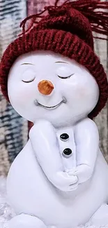 Smiling snowman figurine with red hat on a wooden background.