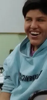 Smiling teen in a blue hoodie with a joyful expression.