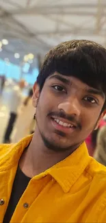 Teen smiling in a vibrant yellow jacket indoors.