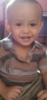 Cute toddler smiling in a striped shirt indoors.