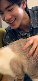 Person smiling while petting a cat on a cozy chair.