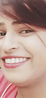 Smiling woman with a pink shirt sitting casually and looking cheerful.