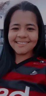 Smiling woman in a red striped shirt posing outdoors.