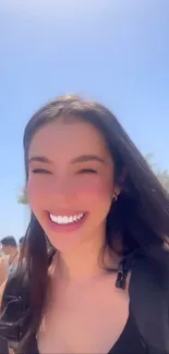 Woman smiling on a sunny beach day, palm trees in background.