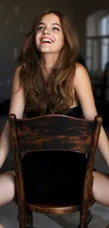 Smiling woman sitting on a wooden chair in a modern room.